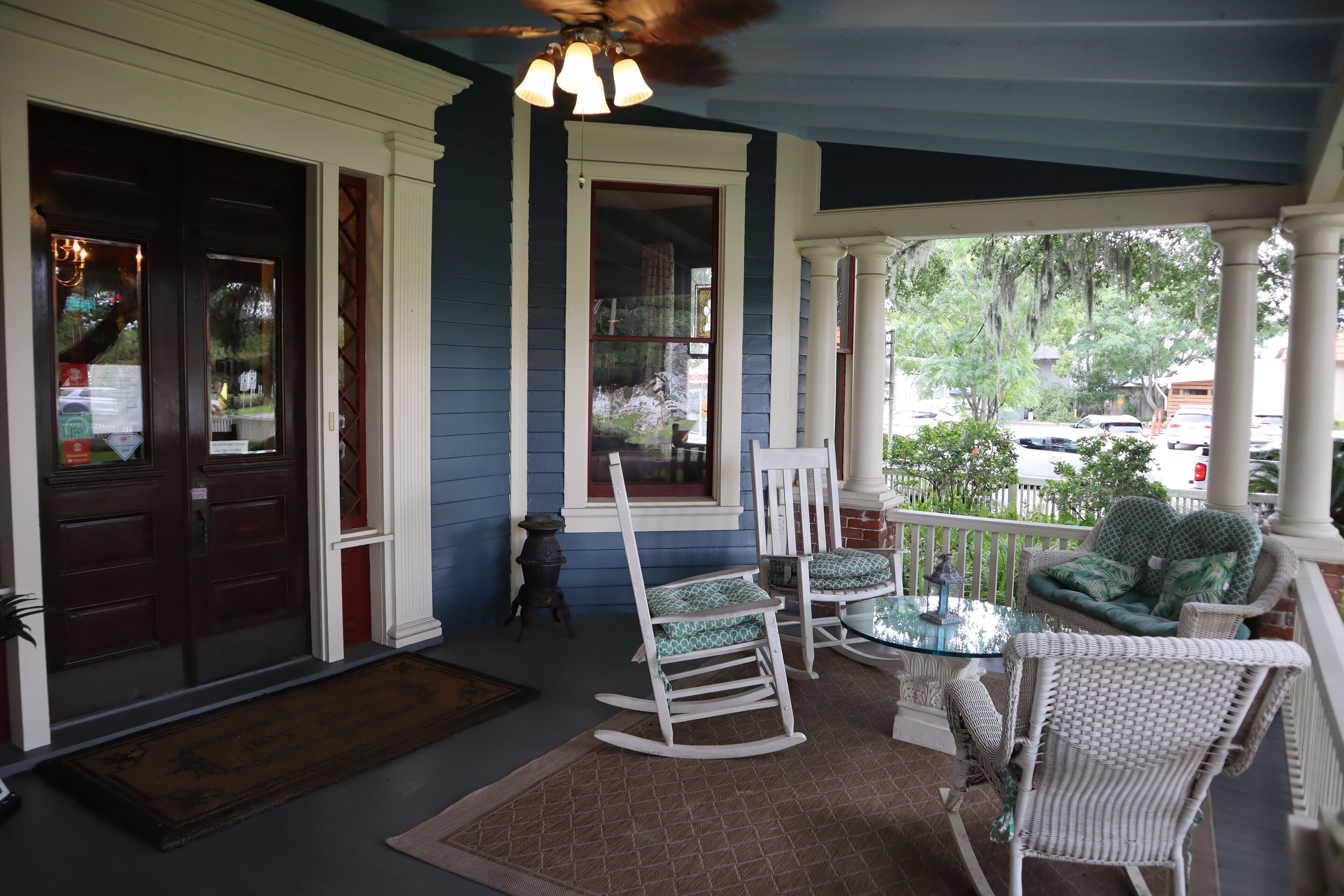 A porch with rocking chairs, a table, and a bench.