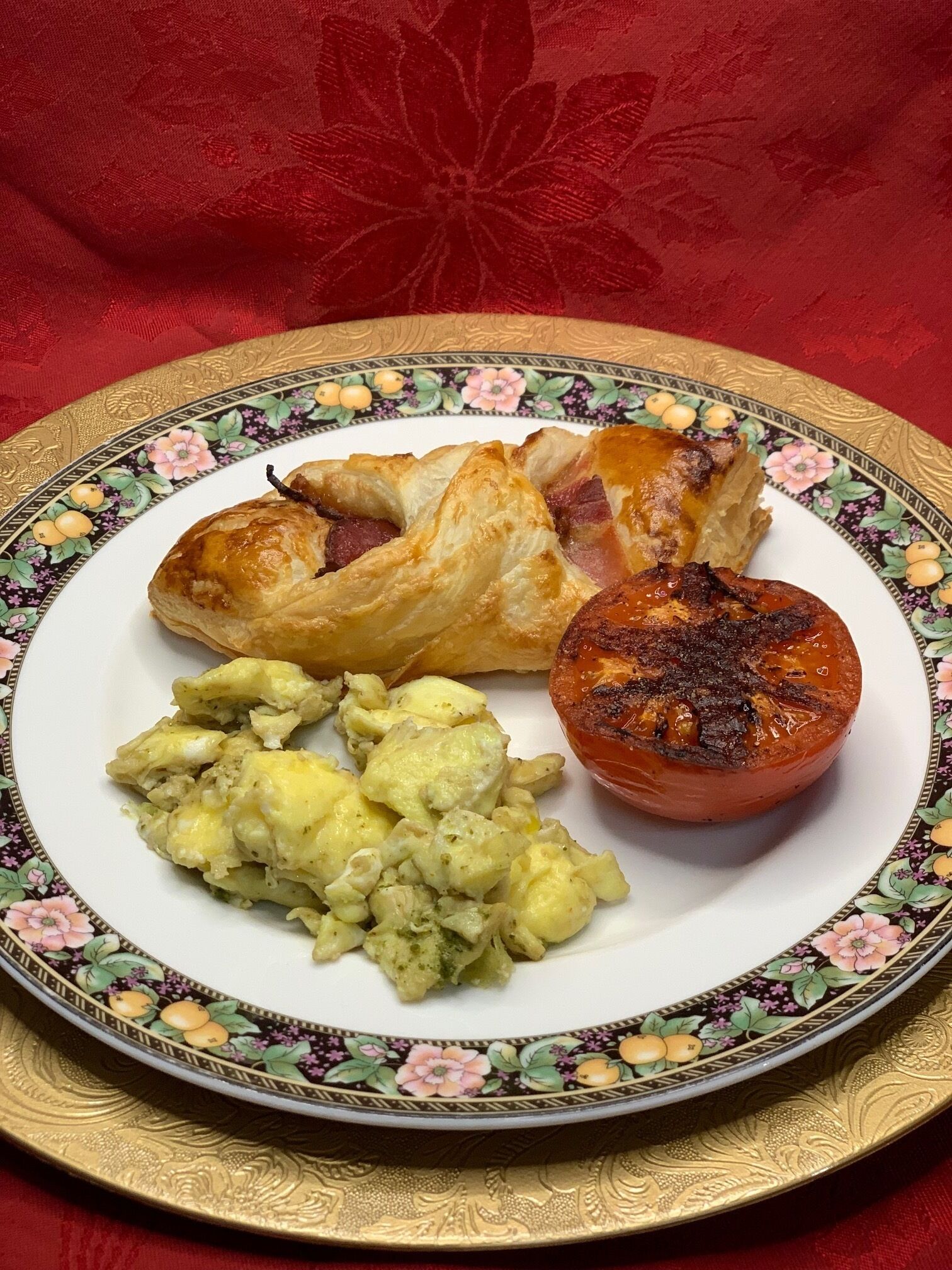 Um prato com um pastel, um tomate assado e uma salada de batata.