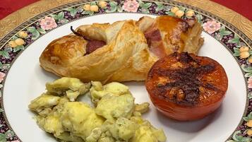 Um prato com um pastel, um tomate assado e uma salada de batata.