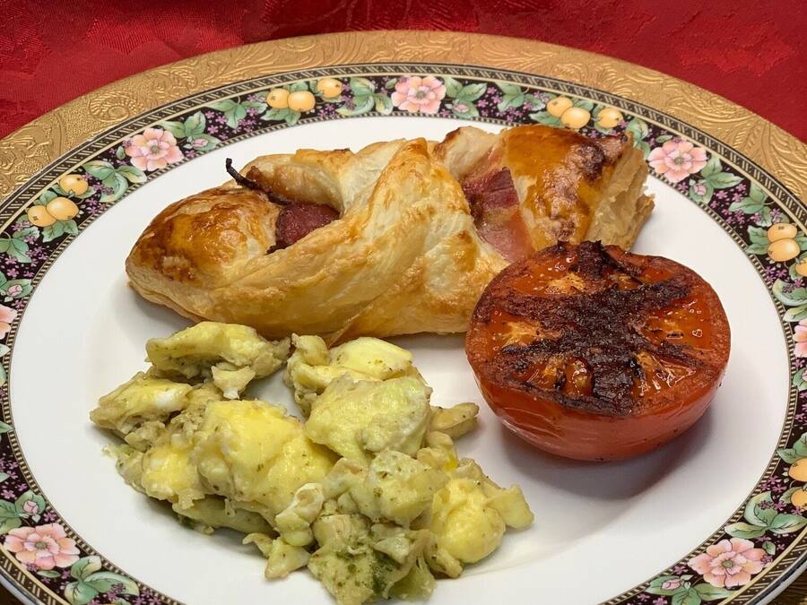 Um prato com um pastel, um tomate assado e uma salada de batata.