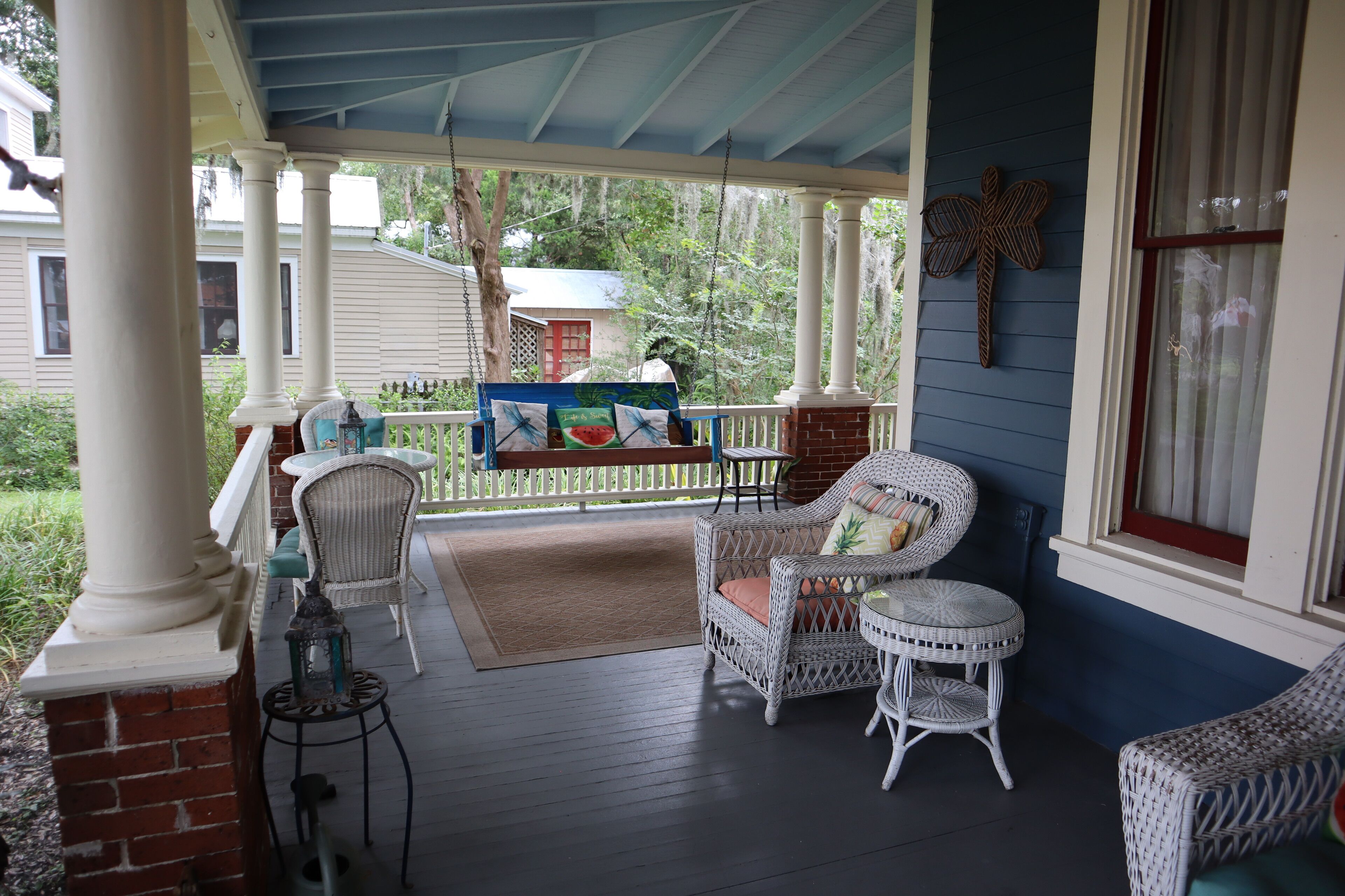 A covered porch with wicker furniture, a small table, and a decorative lantern.