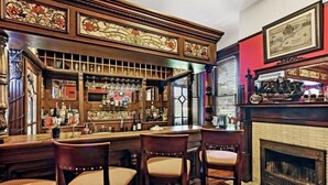 A bar area with wooden bar stools, a fireplace, and a brick wall. - Hoyt House Amelia Island (Fernandina Beach)