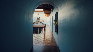 A narrow hallway with a tiled floor and a wooden ceiling.