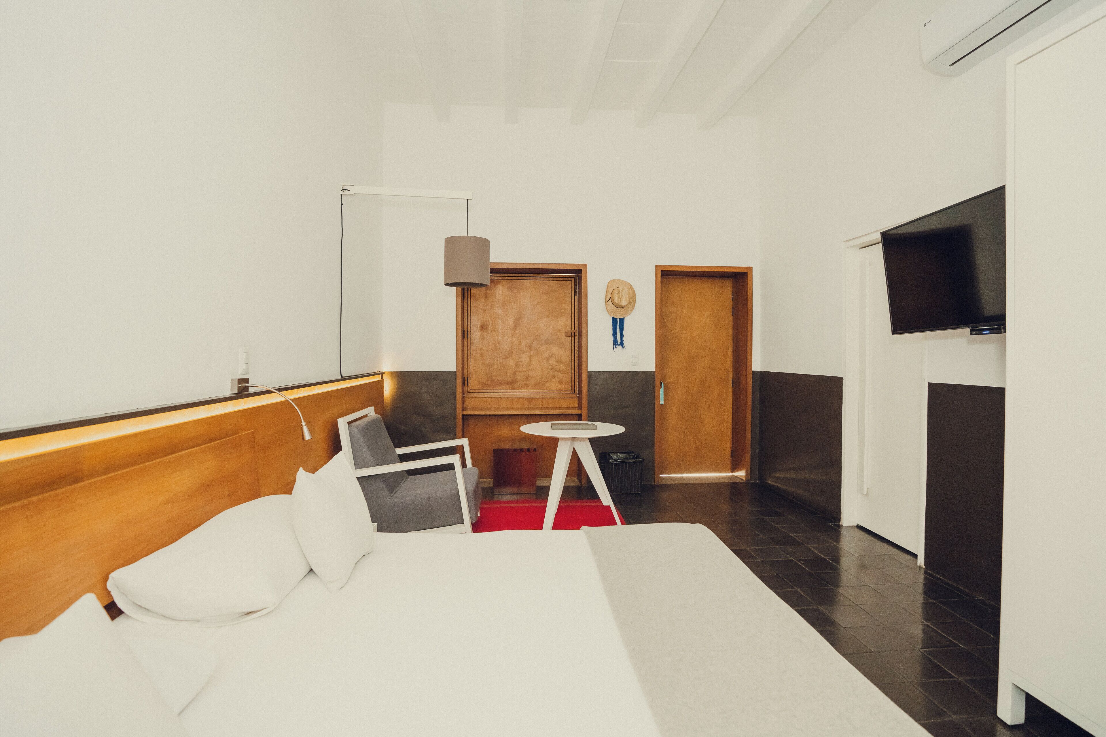 A modern hotel room with a bed, a desk, a chair, a TV, and a wardrobe.