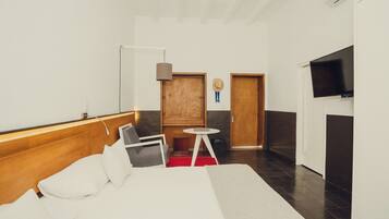 A modern hotel room with a bed, a desk, a chair, a TV, and a wardrobe.