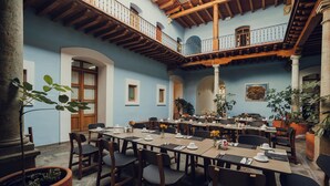 A spacious dining area with multiple tables and chairs, a balcony with wooden railings, and potted plants.