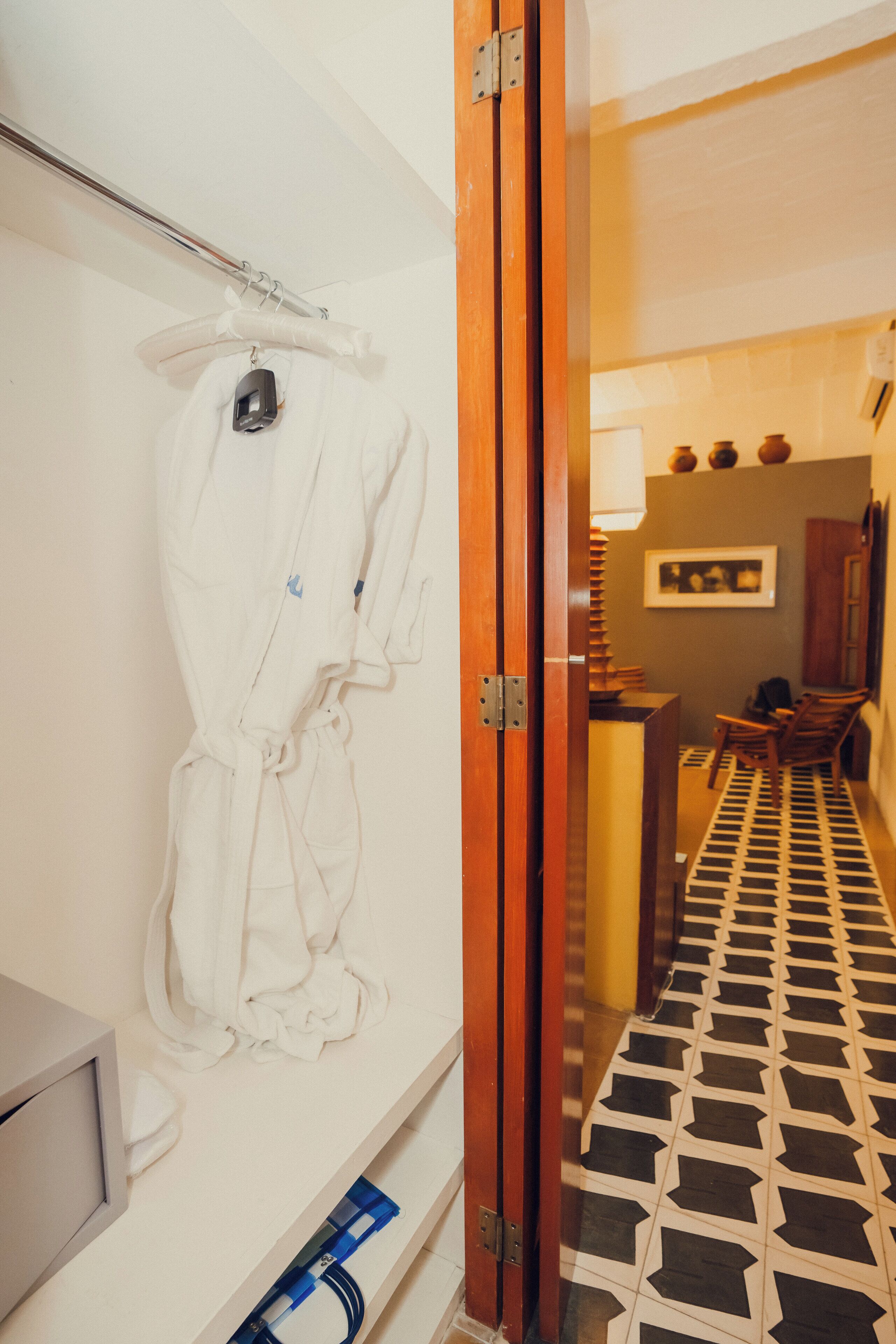 Un baño con bata blanca colgada en un perchero, un lavabo y suelo de baldosas.
