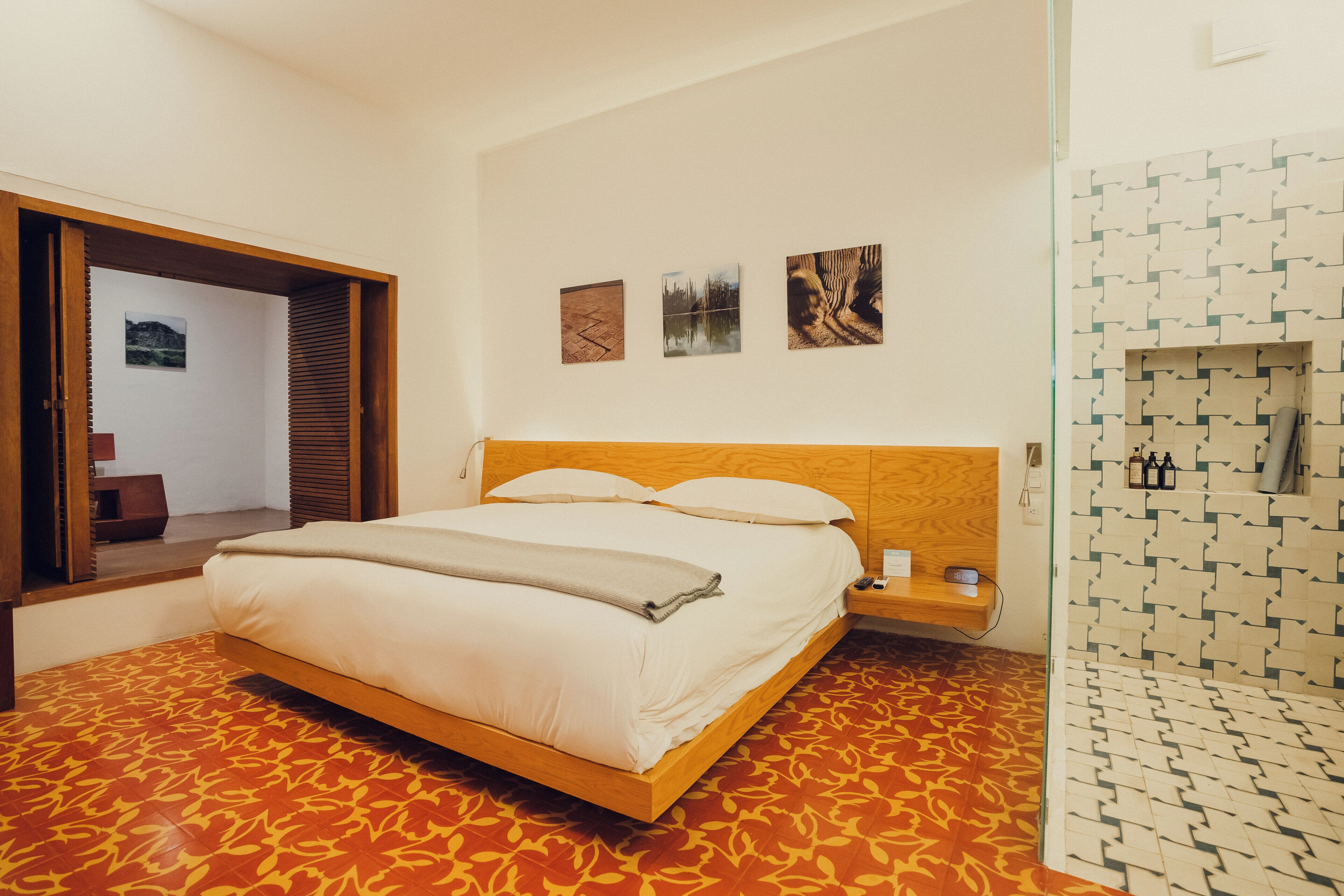 A bedroom with a wooden bed, a small bedside table, and a wall-mounted shelf.