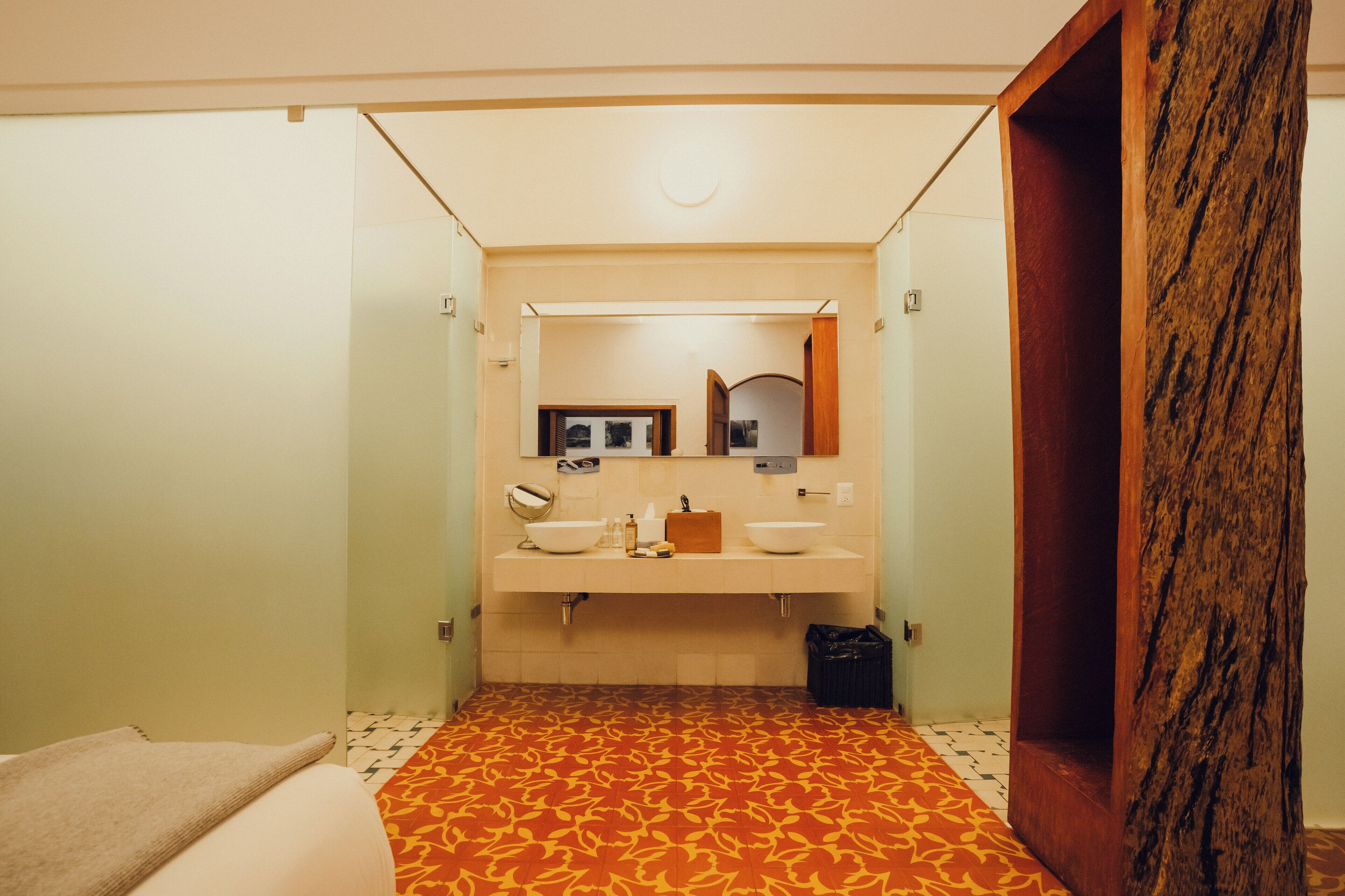 A bathroom with a patterned floor, a sink with a mirror, and a wooden accent wall.
