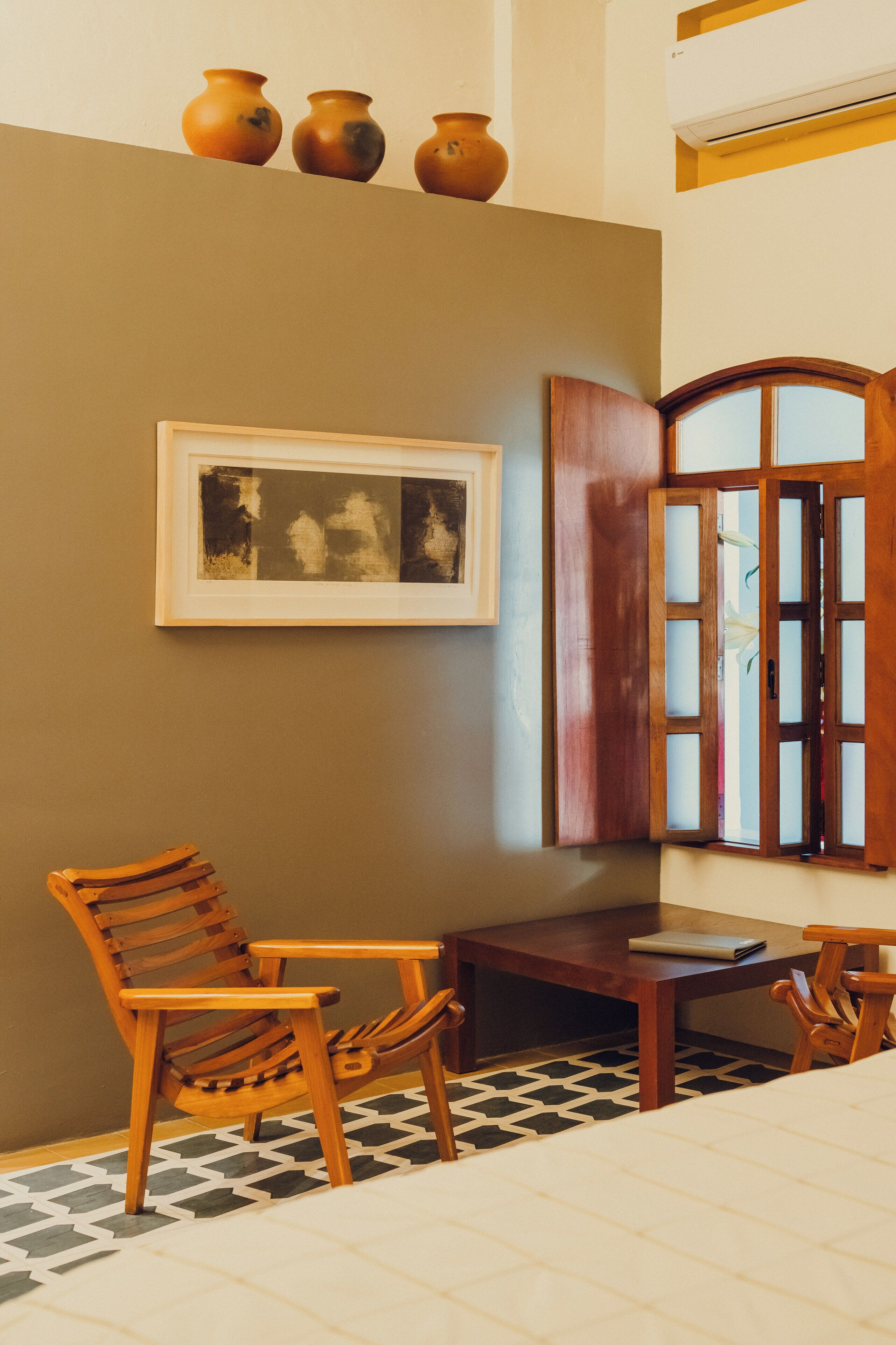 A room with a wooden chair, a small table, a framed picture on the wall, and a cabinet with glass doors.