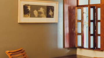A room with a wooden chair, a small table, a framed picture on the wall, and a cabinet with glass doors.