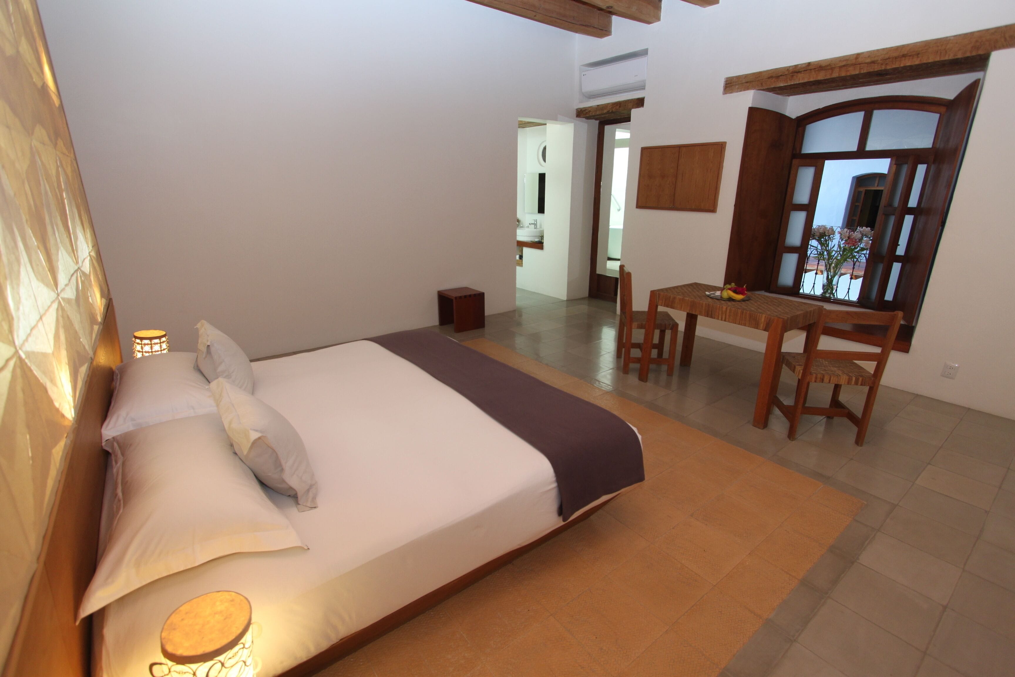 A bedroom with a bed, bedside table, and a desk with chairs.
