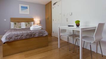 Ein Hotelzimmer mit Bett, Nachttisch, Lampe und Schreibtisch mit Stühlen.
