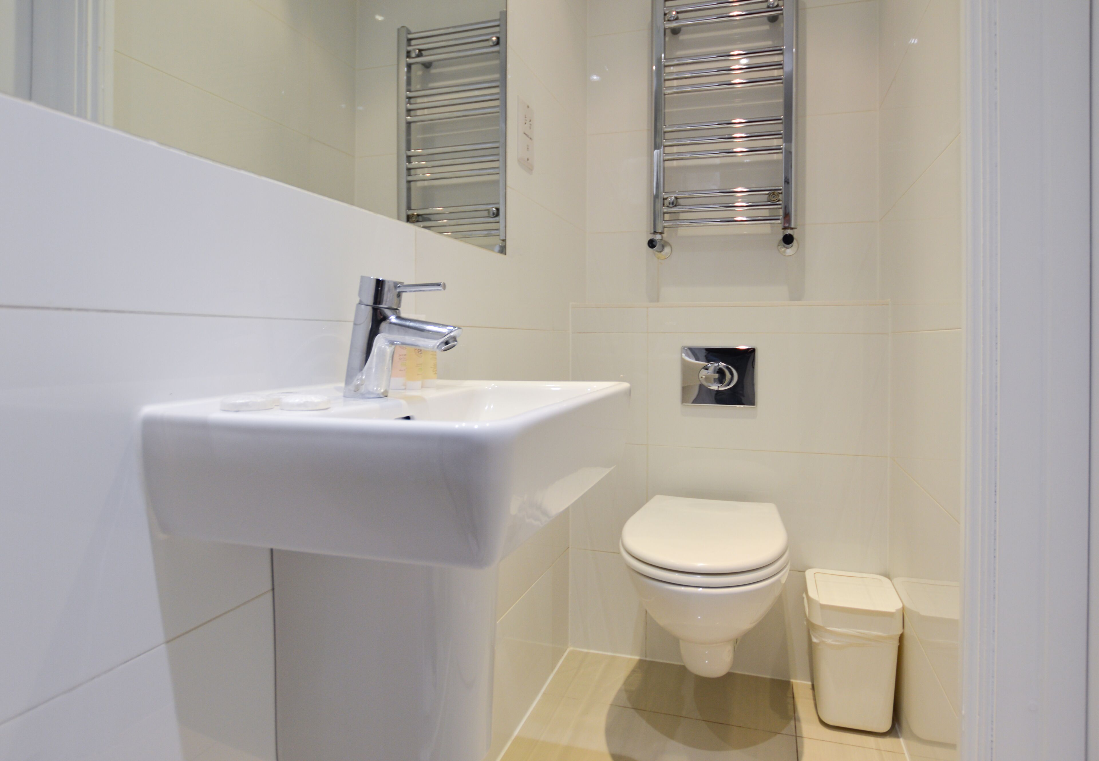 A modern bathroom with a white sink, chrome faucet, and a toilet.