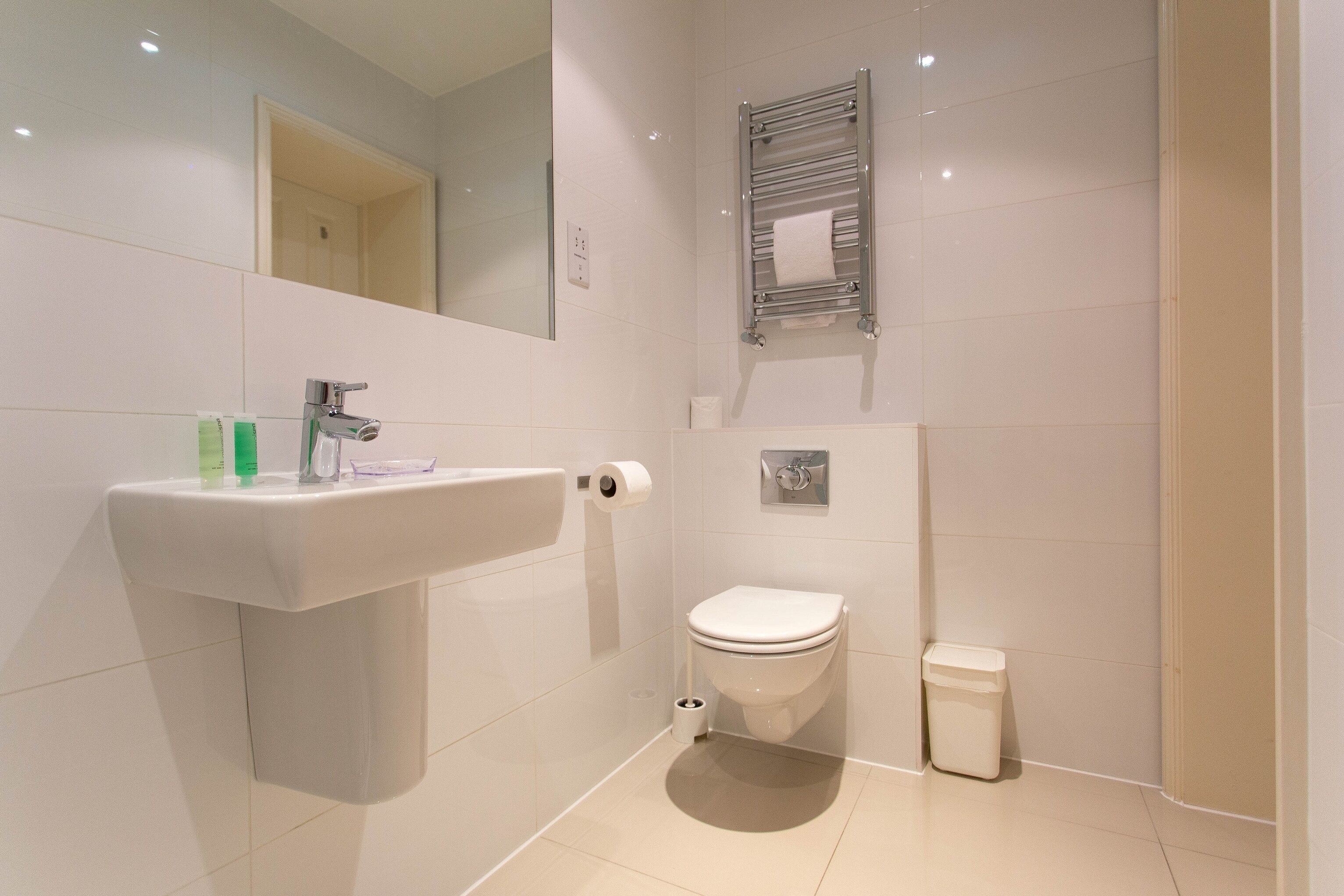 Ein modernes Badezimmer mit Waschbecken, Toilette und Handtuchhalter.