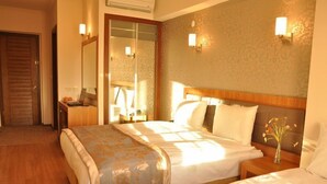 A hotel room with two beds, a wooden headboard, a nightstand, a desk, and a mirror. - Grand Anzac Hotel (Çanakkale)