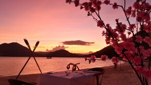 Mesa para dos con vista a una puesta de sol sobre el agua y montañas.