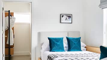 Un dormitorio con cama, un cuadro en la pared y un armario con ropa colgada.