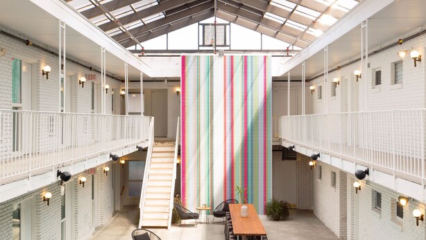 Un amplio espacio interior con piscina, zonas de estar y una escalera que sube a un nivel superior.