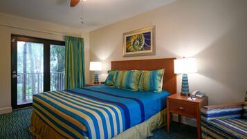 A hotel room with a large bed, two bedside tables with lamps, a chair, a door to a balcony, and a framed picture on the wall.