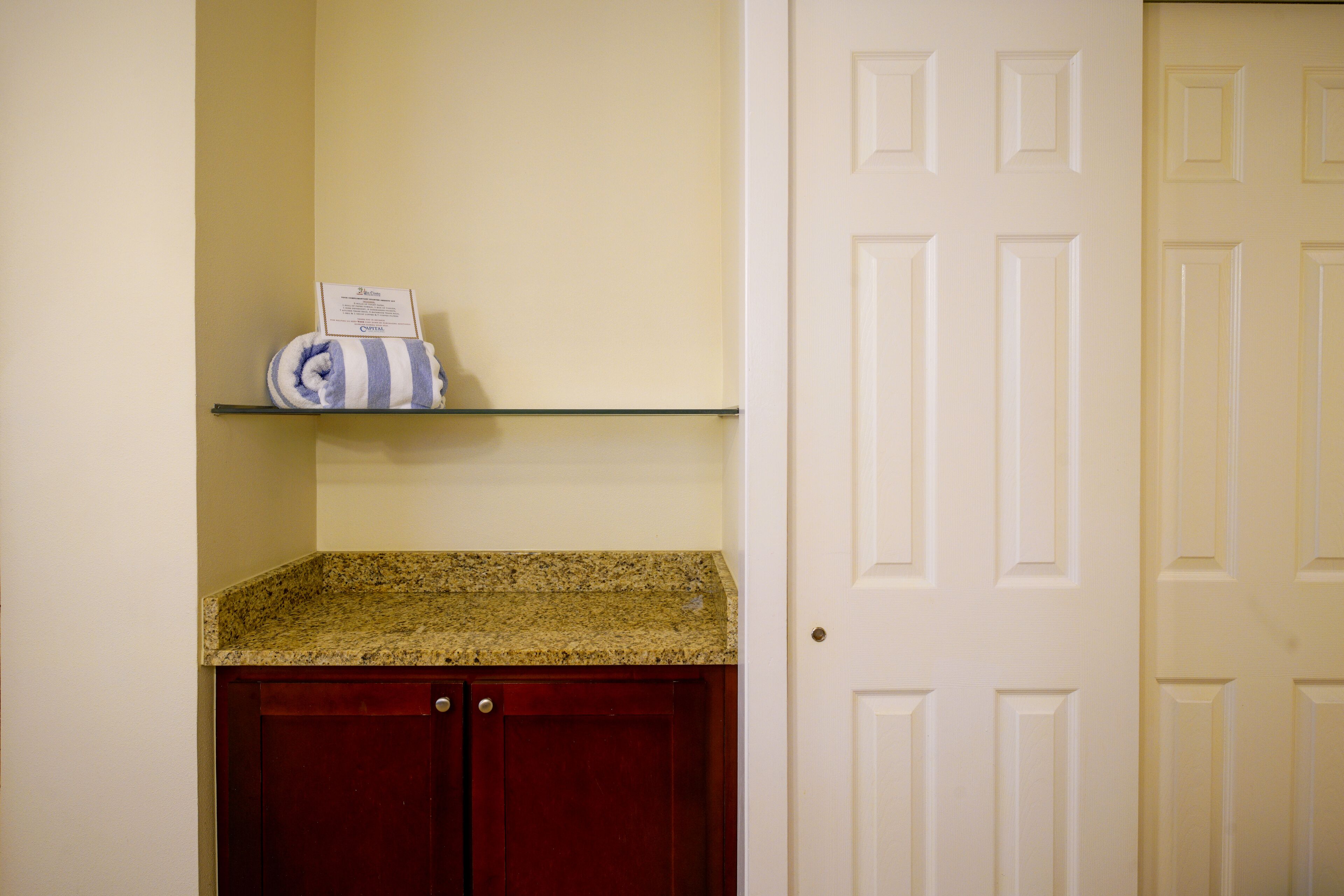 A kitchen with a granite countertop, a red cabinet, and a white door.