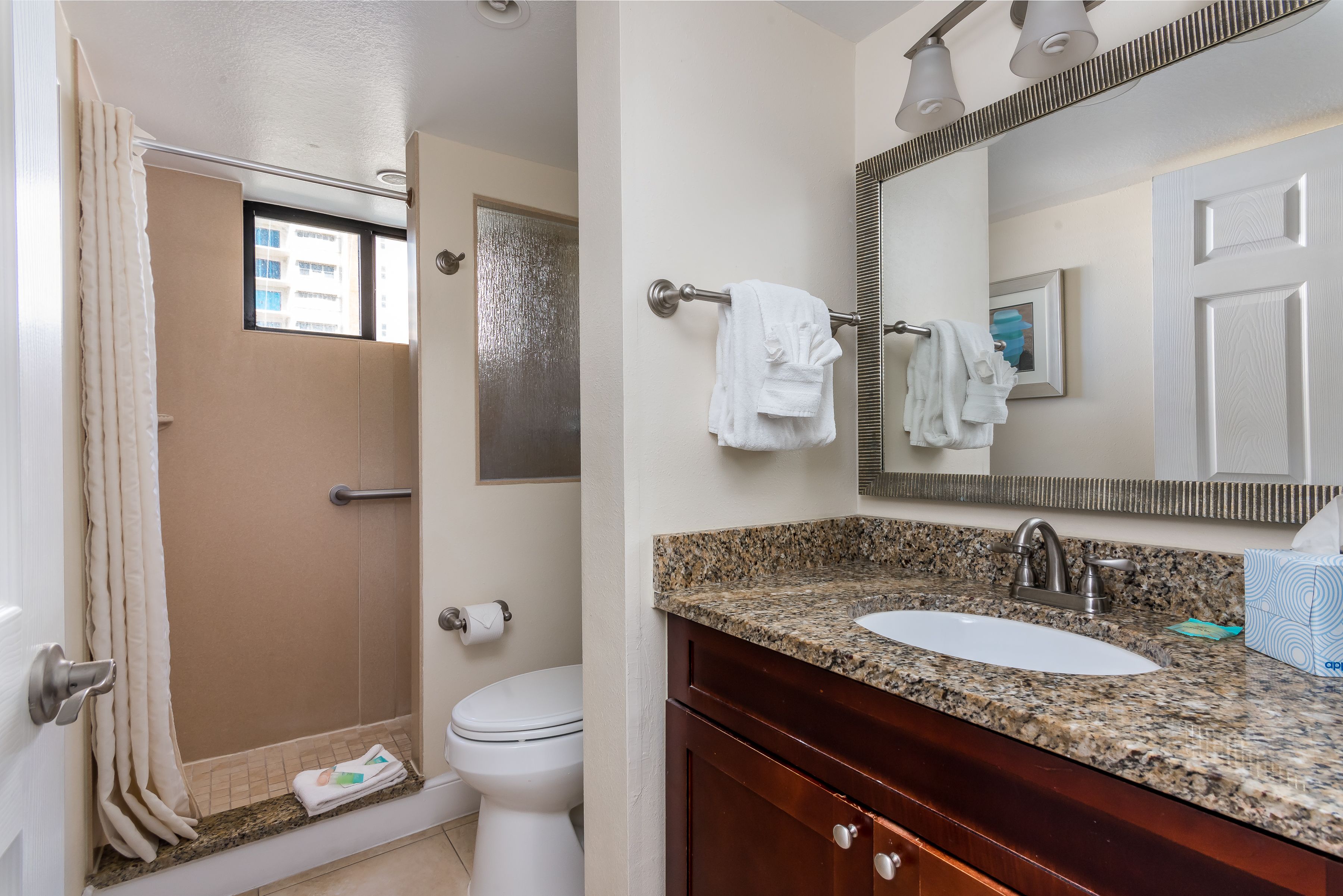 A bathroom with a shower, toilet, sink, and vanity.