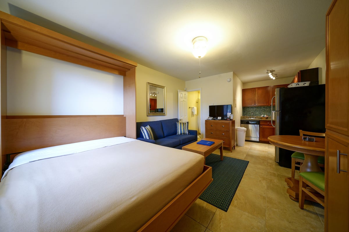 Een hotelkamer met een bed, een slaapbank, een bureau, een televisie en een kitchenette.