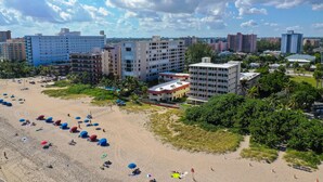 A beach with umbrellas and people, surrounded by buildings. - La Costa Beach Club (Pompano Beach)