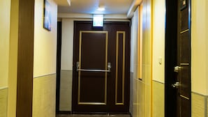 A hallway with wooden flooring, a door with a sign above it, and a ceiling light. - Luckynews Classic Hotel (Taoyuan City)