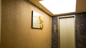 An elevator with a modern design, a patterned wall, and a ceiling light. - Luckynews Classic Hotel (Taoyuan City)