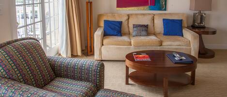 A living room with a beige sofa, patterned armchair, and a round coffee table.