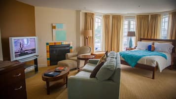 Une chambre d’hôtel équipée d’un lit, d’un canapé, d’un fauteuil, d’une télévision et d’une cheminée.