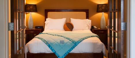 A hotel room with a bed, nightstands, lamps, and a carpeted floor.