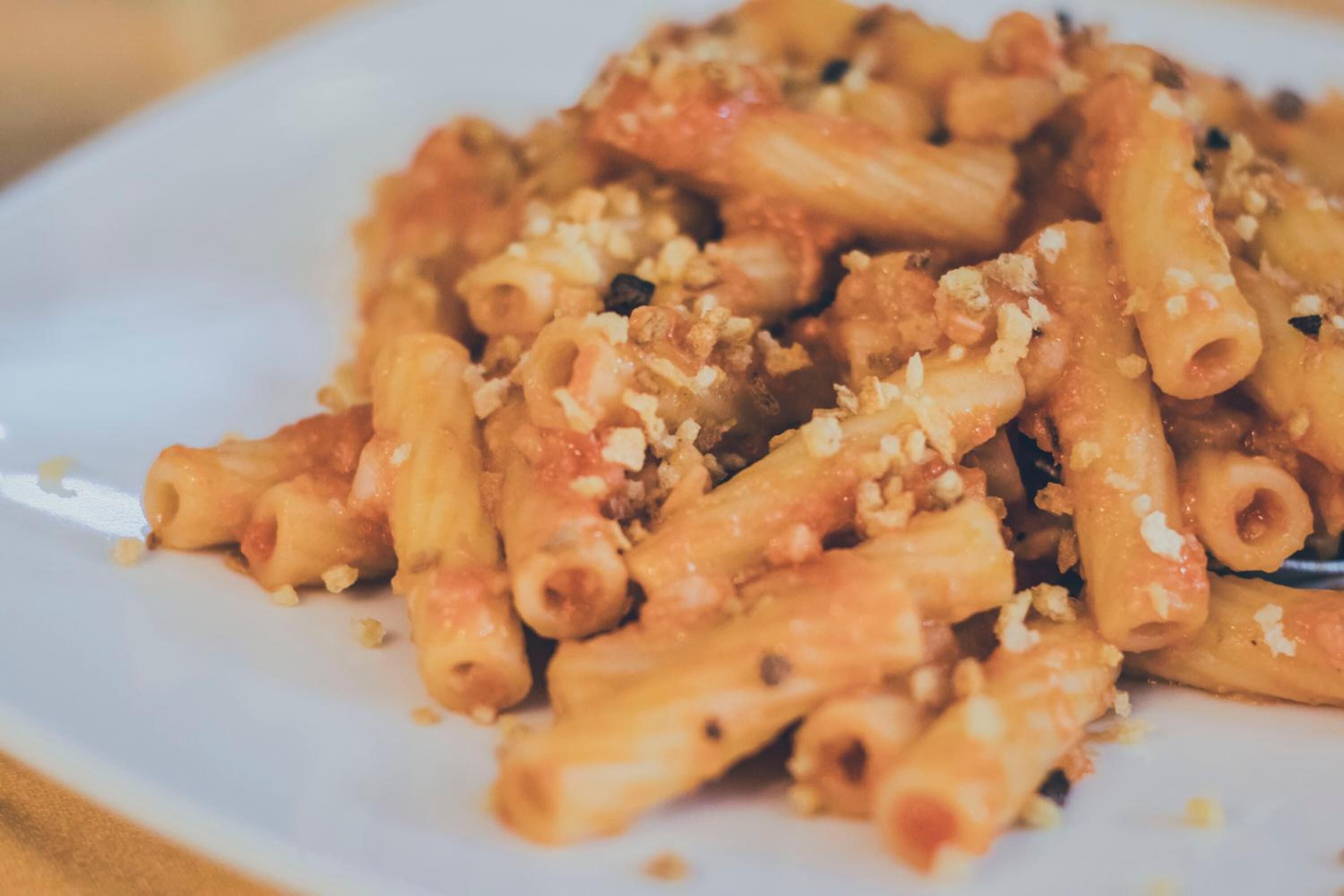 A plate of pasta with a tomato-based sauce and grated cheese.