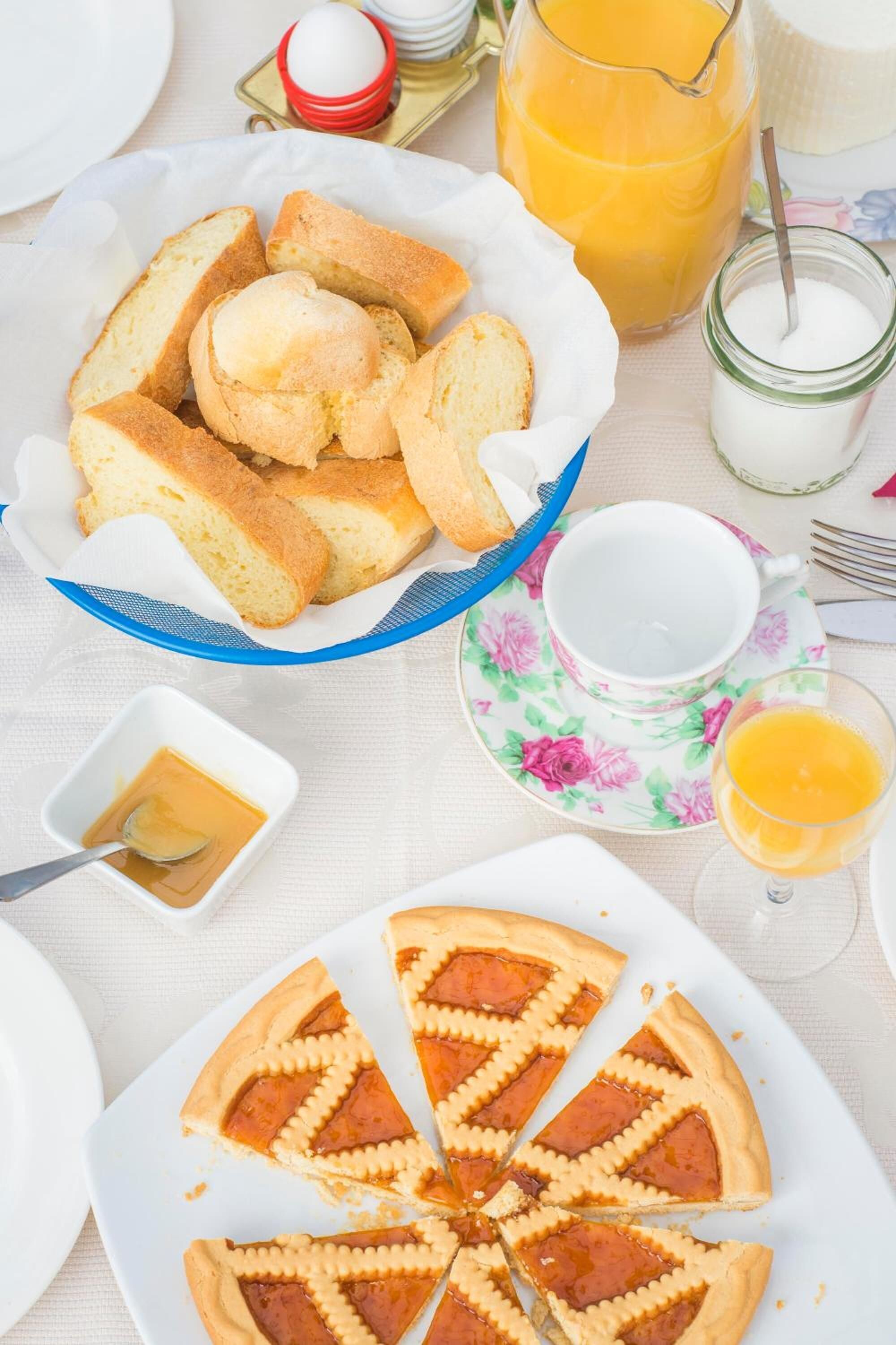 A breakfast setting with a plate of toast, a pie, a jug of orange juice, a glass of milk, and a cup of coffee.
