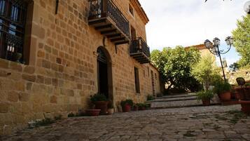 Un edificio in pietra con un cortile in pietra, piante in vaso e una scala che conduce al secondo piano.