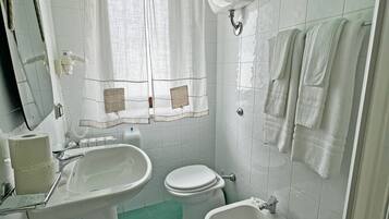Un baño con inodoro, bidé, lavabo y espejo.