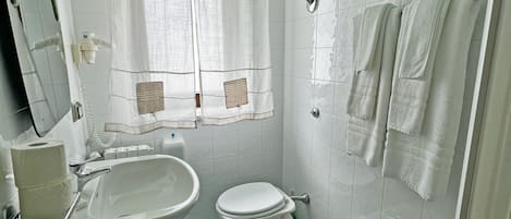 A bathroom with a toilet, bidet, sink, and a mirror.