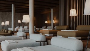 Ein modernes Spa mit verschiedenen Sitzbereichen, darunter Sofas und Sessel, sowie mehreren Stehlampen, die für stimmungsvolle Beleuchtung sorgen.
