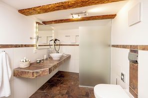 Un baño moderno con tocador, lavabo, espejo, ducha e inodoro.