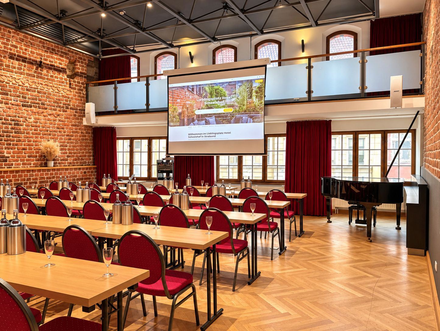 A conference room with a large screen, tables, chairs, and a grand piano.