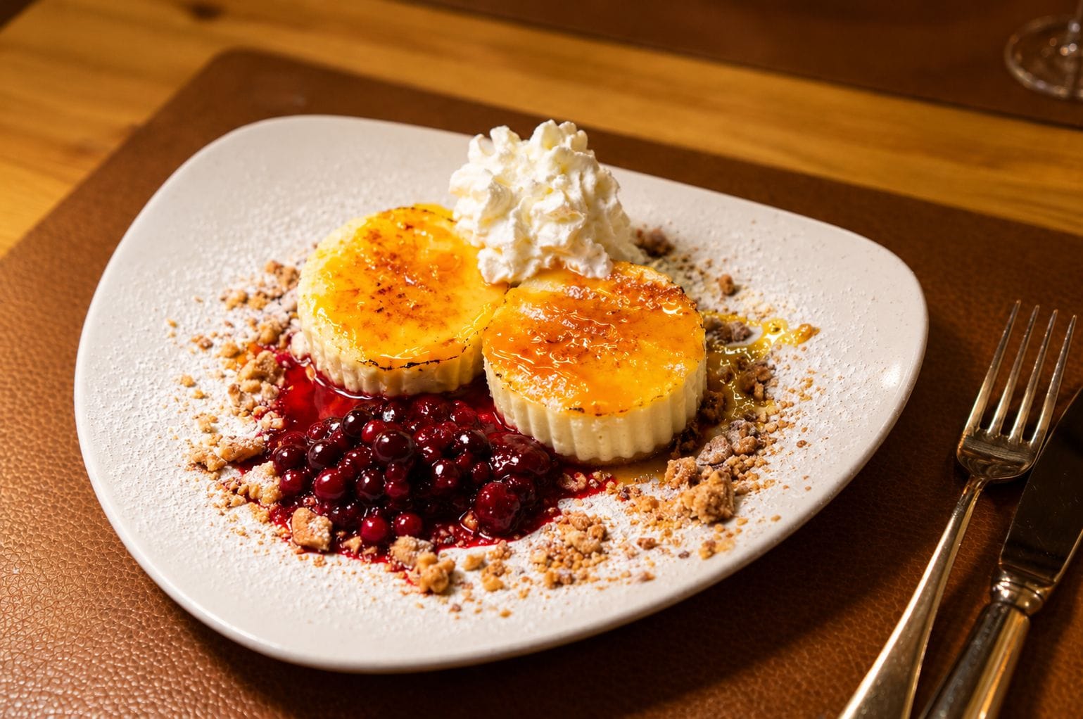 Een nagerechtenbord met een romig dessert, bessen en een toefje slagroom.