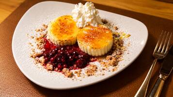 Een nagerechtenbord met een romig dessert, bessen en een toefje slagroom.