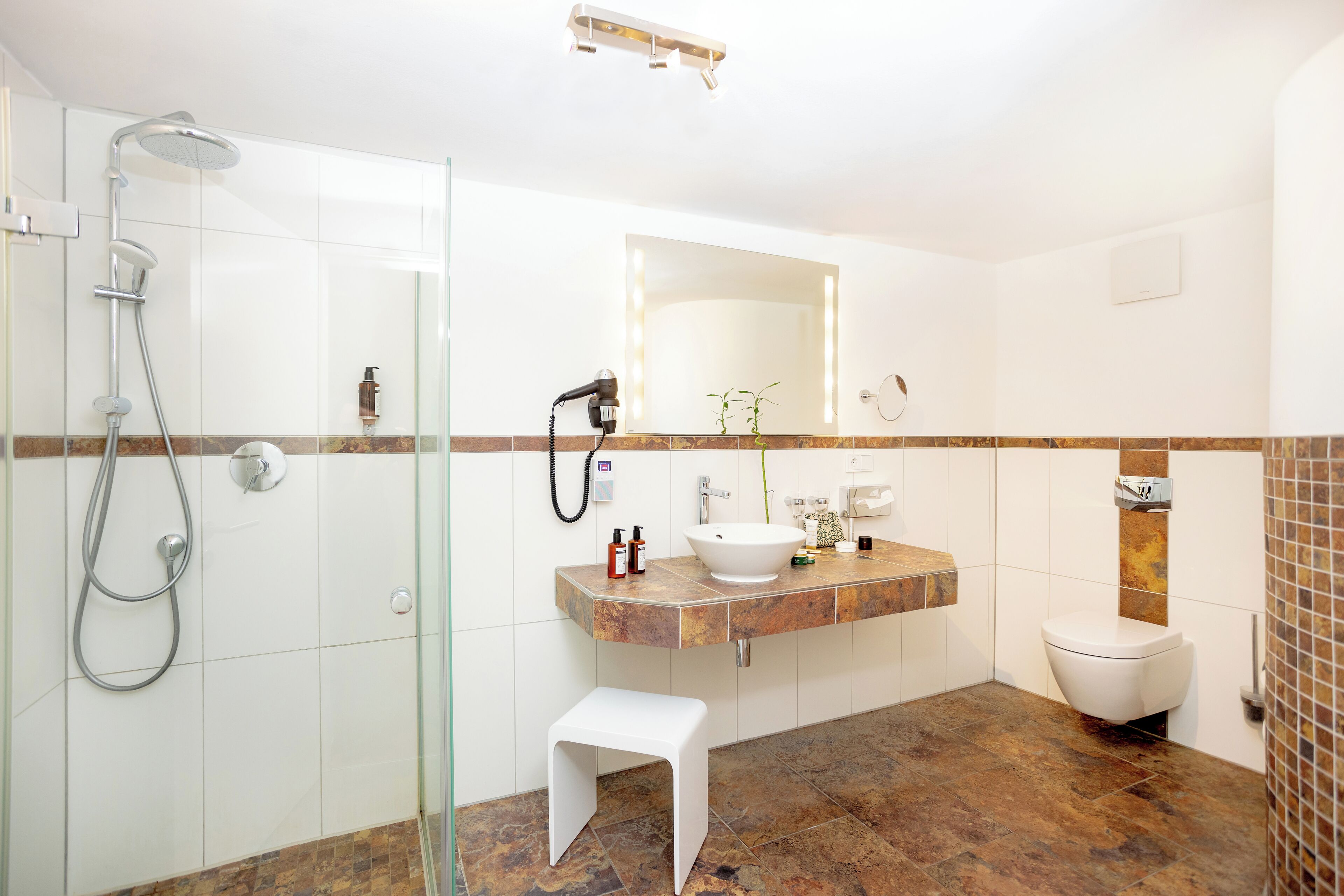 Une salle de bain moderne avec une douche à parois de verre, un lavabo blanc, un meuble-lavabo avec un miroir et des toilettes.