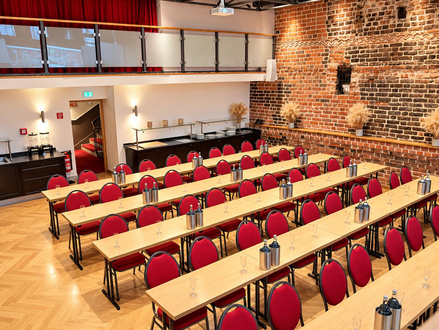 A conference room with multiple tables and chairs, a brick wall, and a staircase.