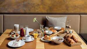 Una mesa de desayuno con diversos alimentos, una taza de café y un vaso de jugo.