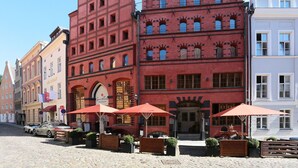 Un edificio rojo con ventanas de arco y un edificio blanco de fachada plana.