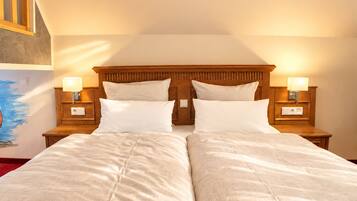 A double bed with two pillows, wooden headboard, bedside lamps, and a painting on the wall.