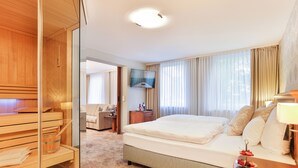 Una habitación de hotel con una cama, un escritorio, un televisor y una zona de sauna.