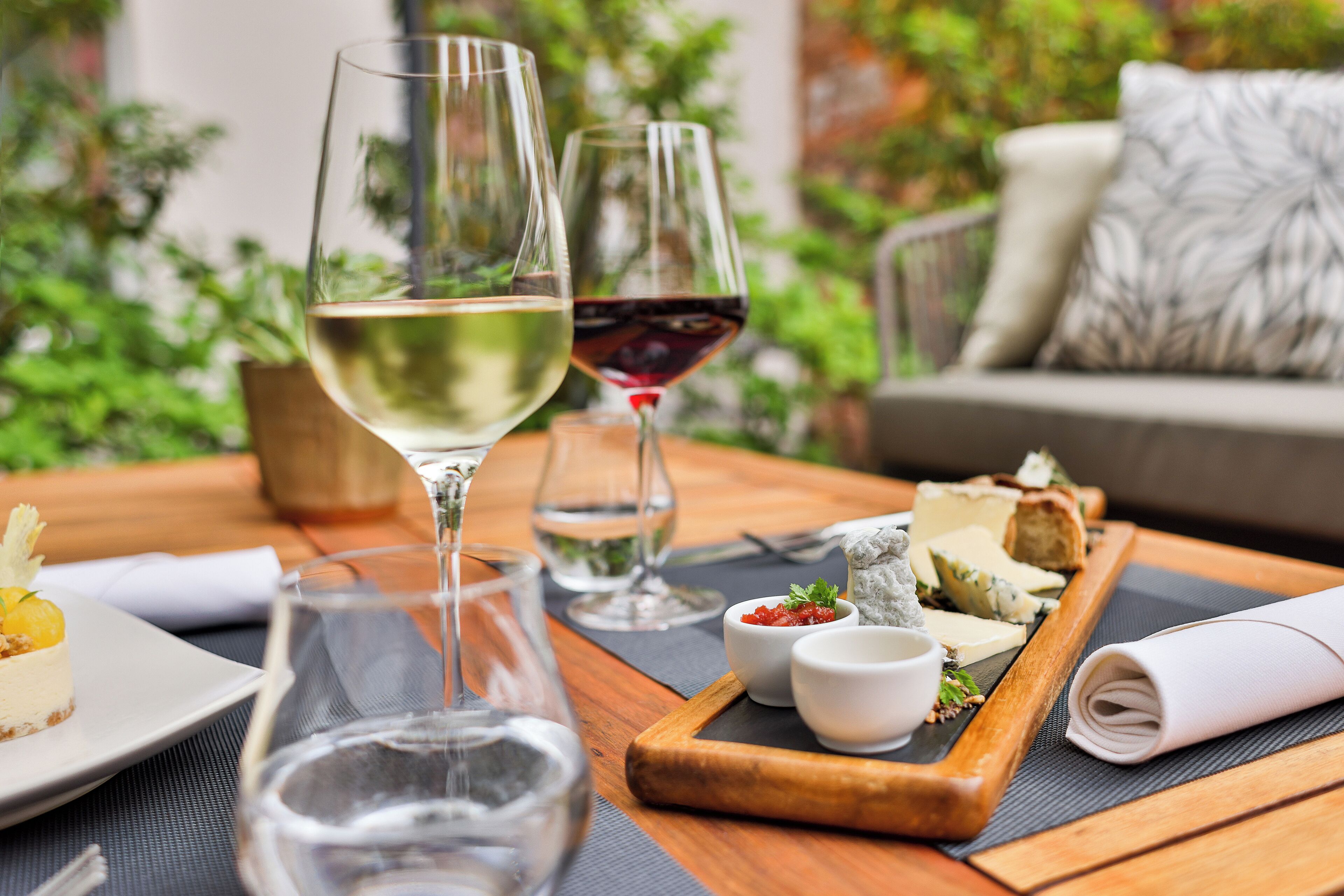 A dining table with wine glasses, a cheese board, and a plate of food.